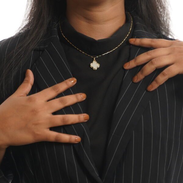 Elegant ivory clover pendant necklace on a woman with black attire.